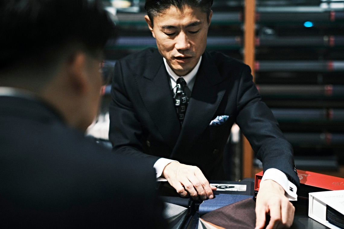 生地見本を前にお客様と向き合うテーラー